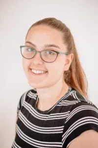 Headshot of Elisa Musson Casting Assistant where glasses and a black and pink striped shirt.